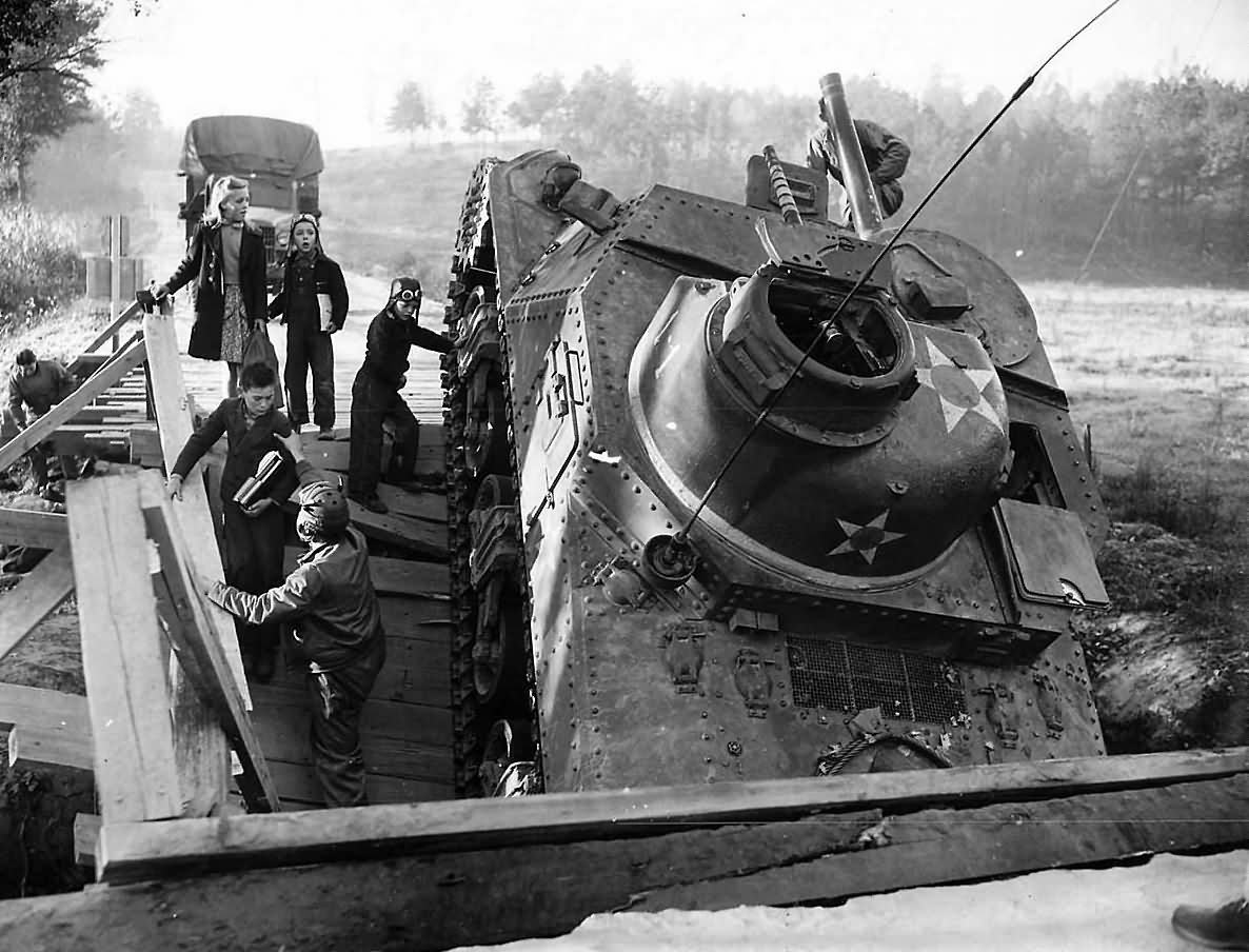 2nd_Armored_Division_Troops_Help_Children_Past_Crashed_M3_lee